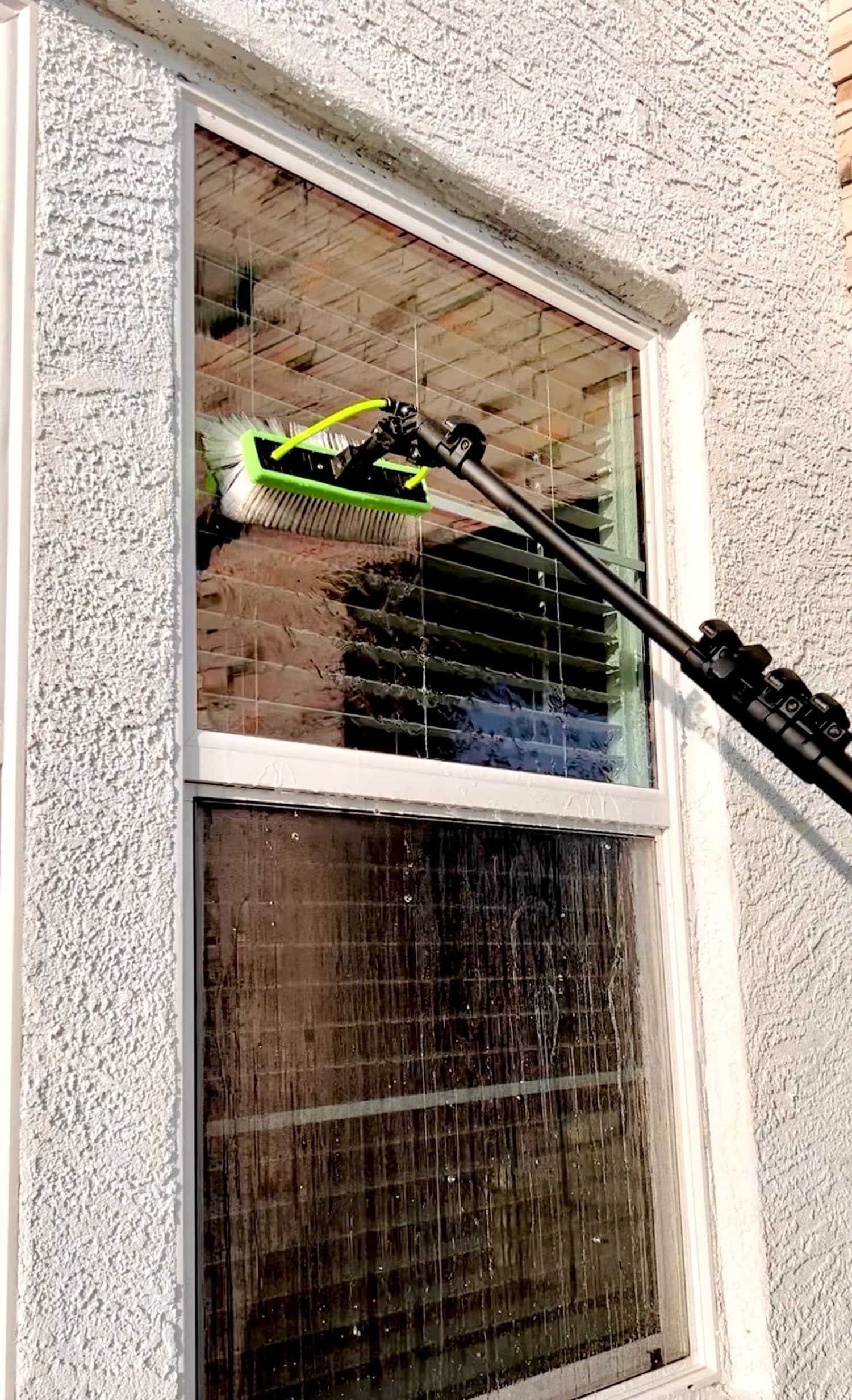 Cleaning a second-story window with a waterfed pole and soft brush